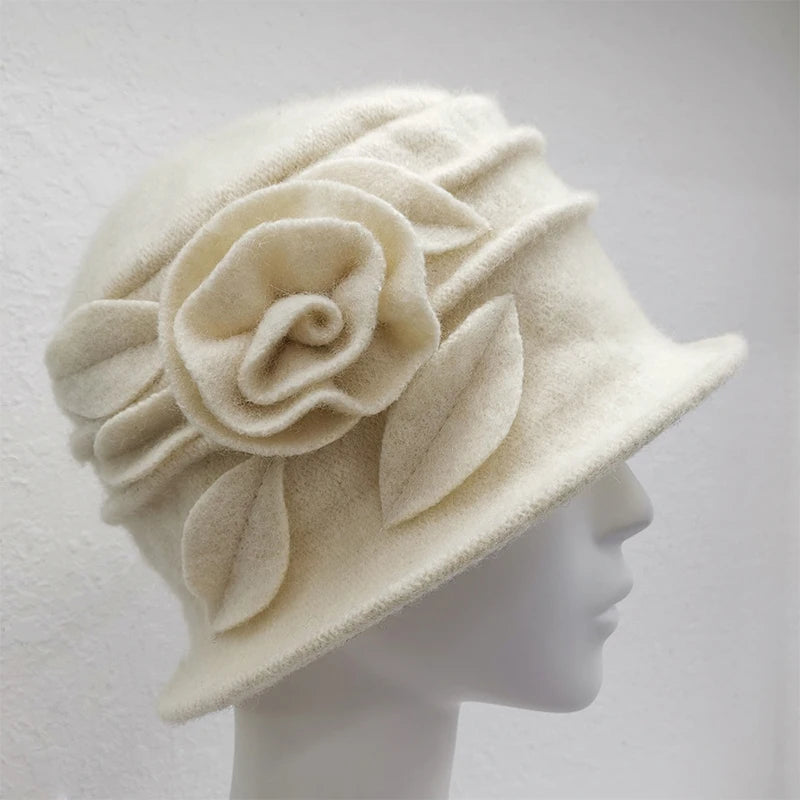 Cream wool cloche hat on a mannequin, featuring a decorative felt flower and leaf design with ribbed detailing.