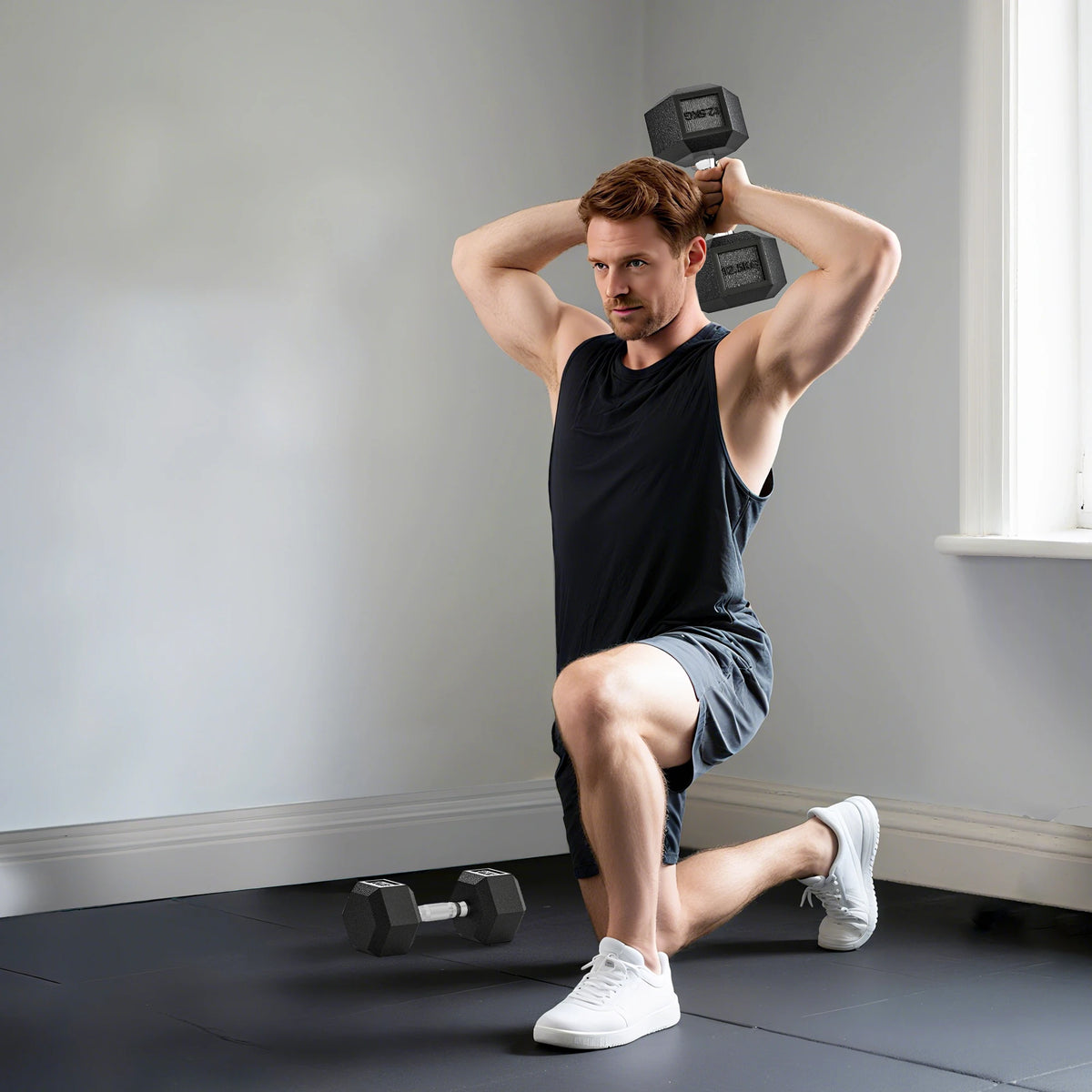 Man lunging while holding a black rubber 12.5kg hex dumbbell overhead, with a second on the floor.