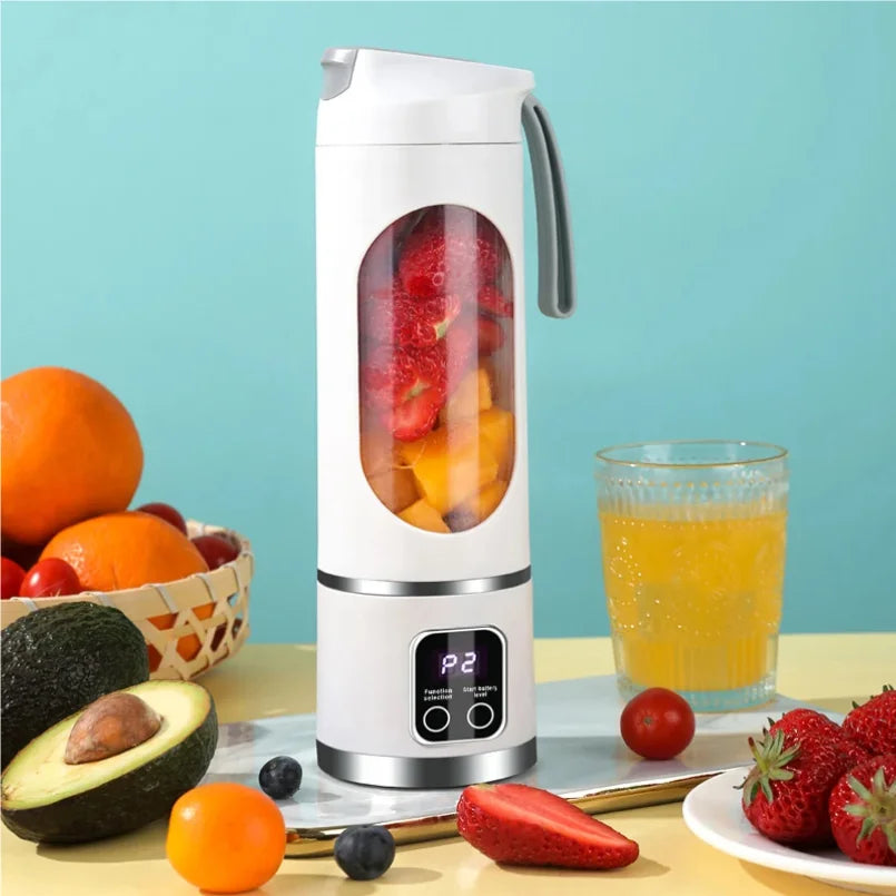 White portable electric blender with a digital display, filled with cut strawberries and mango on a table with fruit.