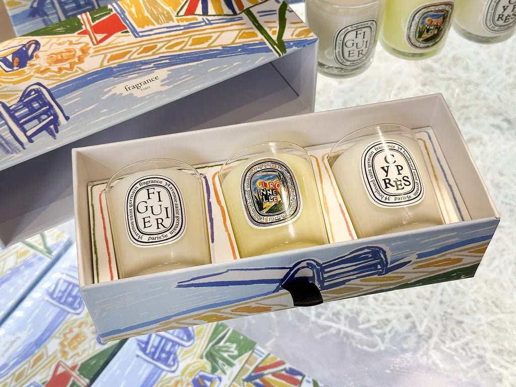 Three mini scented candles in a decorative box featuring an illustrated Mediterranean-style coastal design.