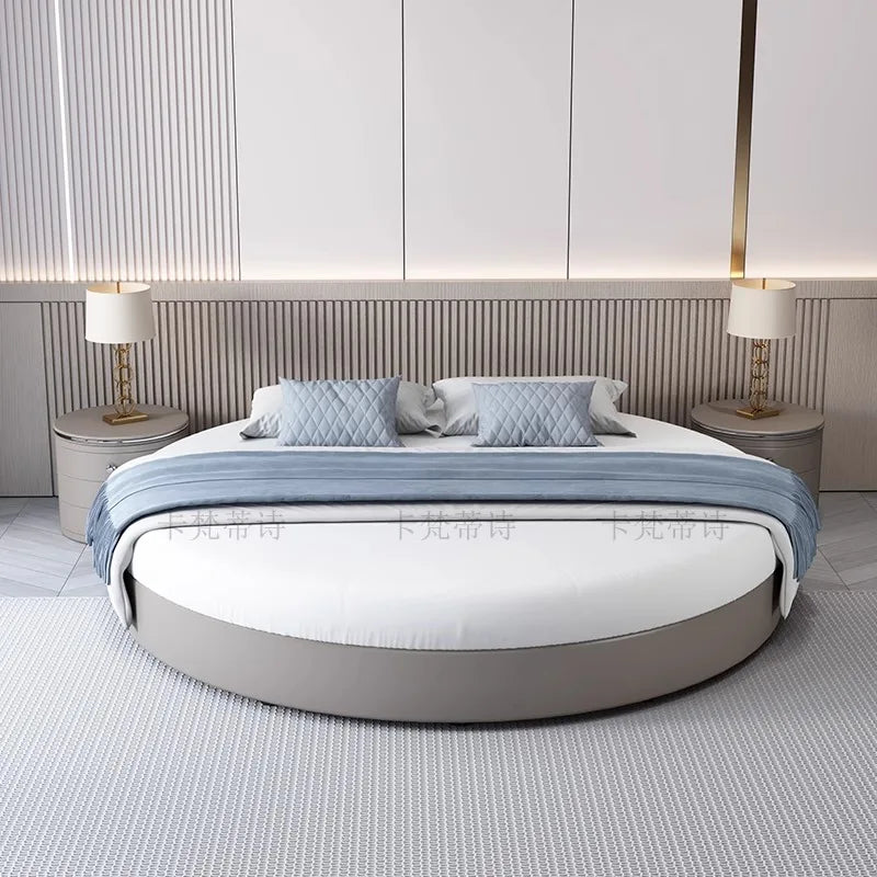 Modern circular grey upholstered bed frame with white bedding, blue throw and two matching bedside tables.