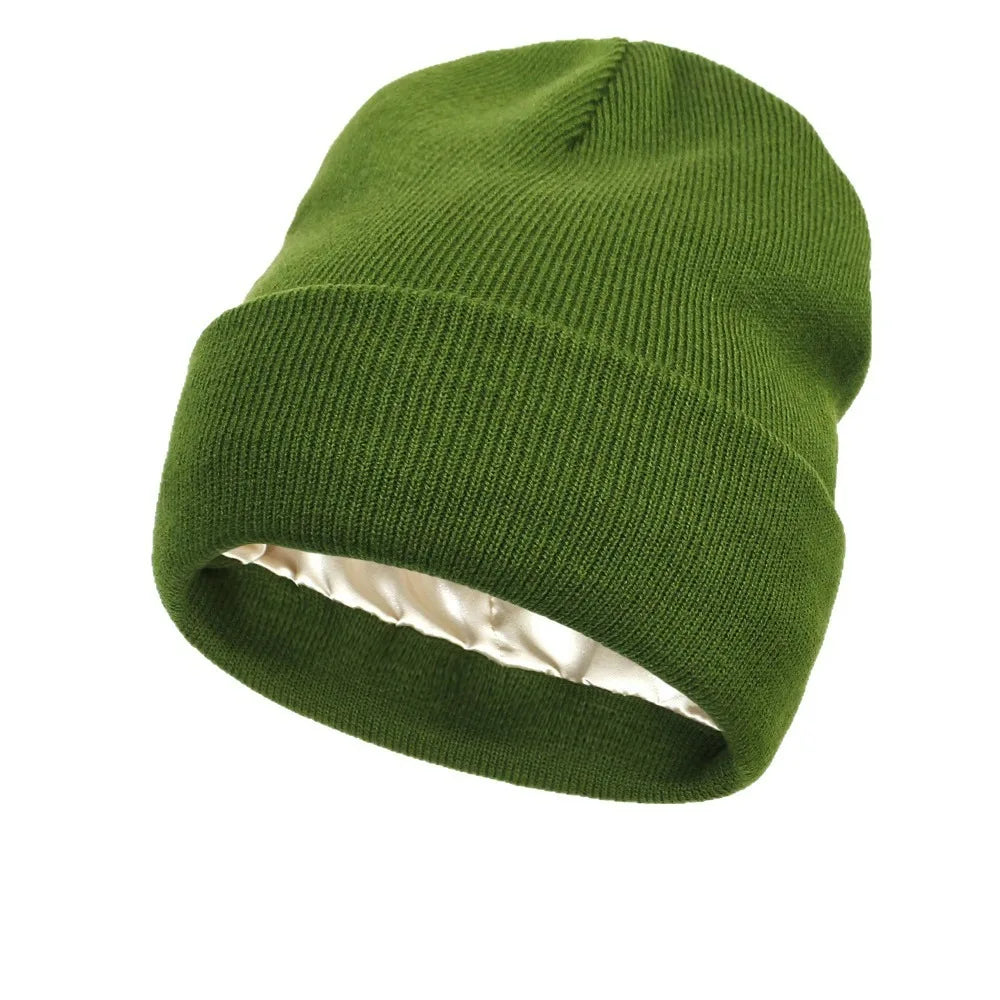 Olive green knitted beanie hat with a smooth, cream-coloured satin lining, isolated on a white background.