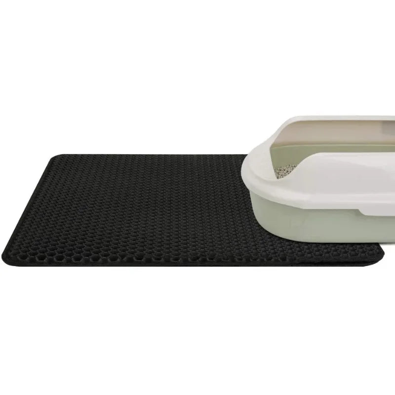 Black, double-layer, waterproof cat litter mat with a honeycomb texture, placed under a litter tray.