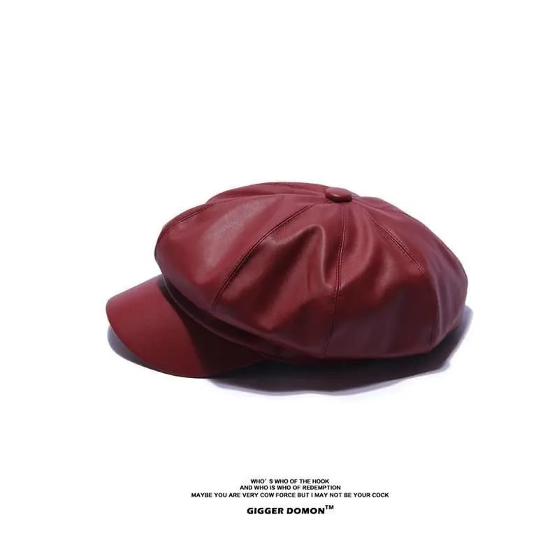 A deep red, faux-leather baker boy cap with a structured peak and paneled crown design.