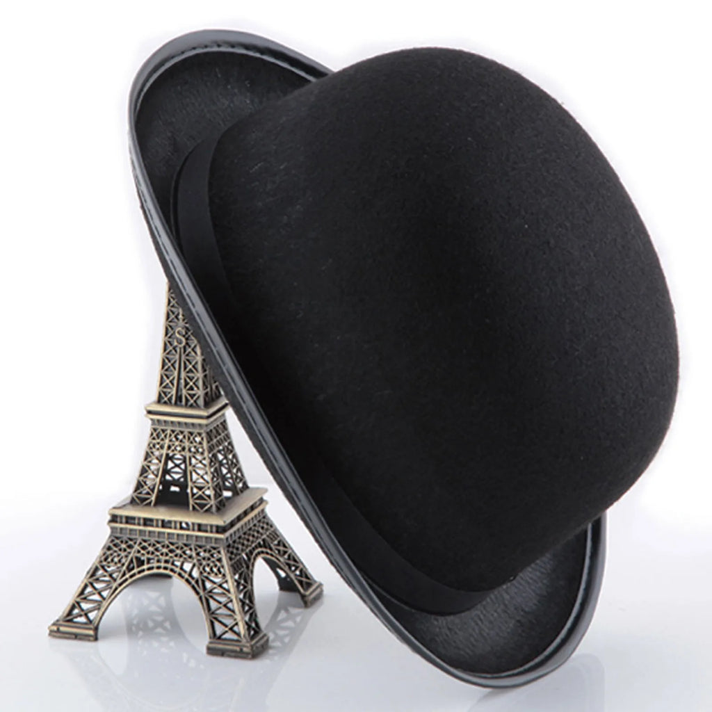 A classic black felt bowler hat balanced on a miniature metal Eiffel Tower model.