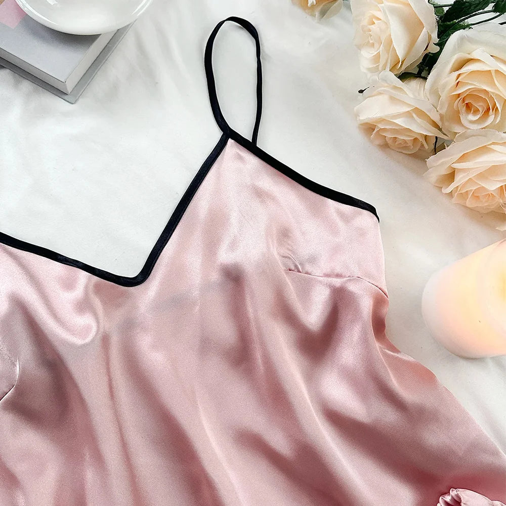 Pink satin camisole top with a V-neck, delicate spaghetti straps, and contrasting black trim detail.