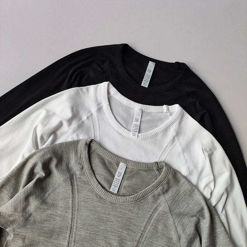 Three long-sleeved athletic tops in black, white, and grey with ribbed necklines and textured seams.
