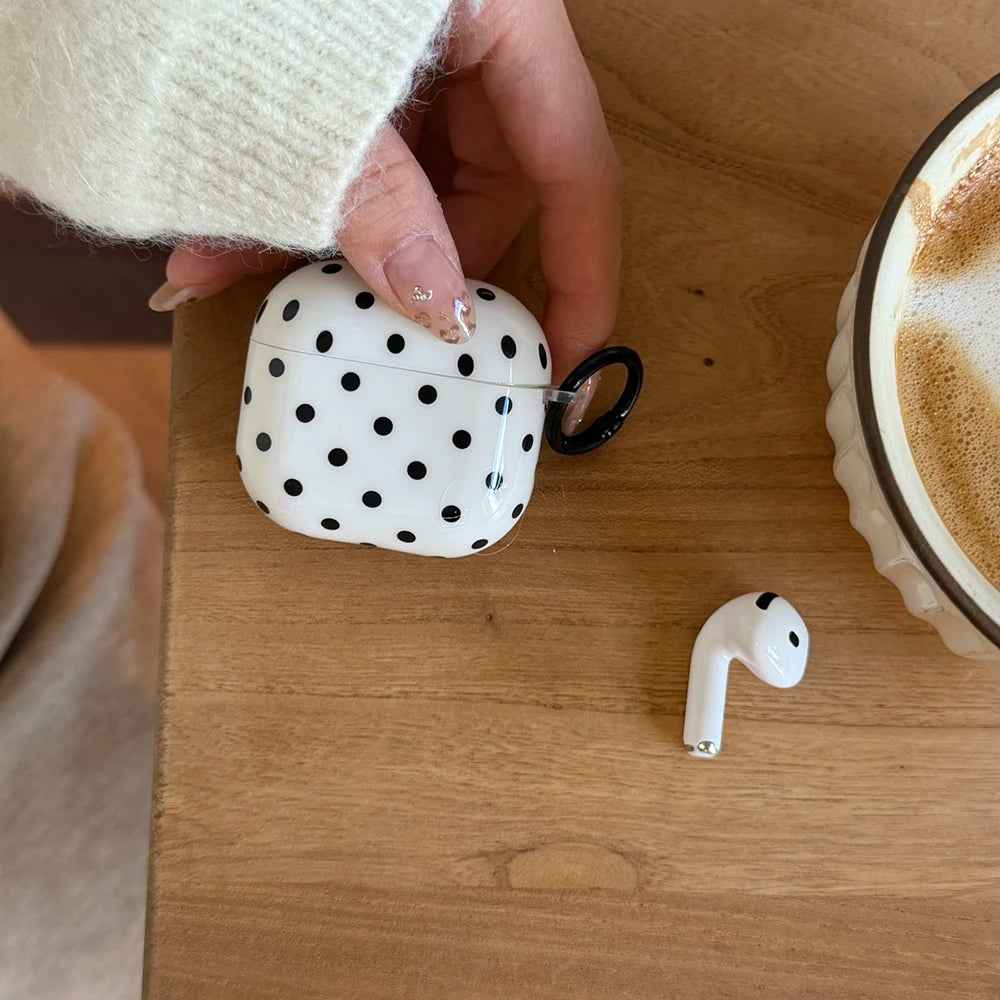 White polka dot glossy plastic case for AirPods, featuring a black side ring loop.