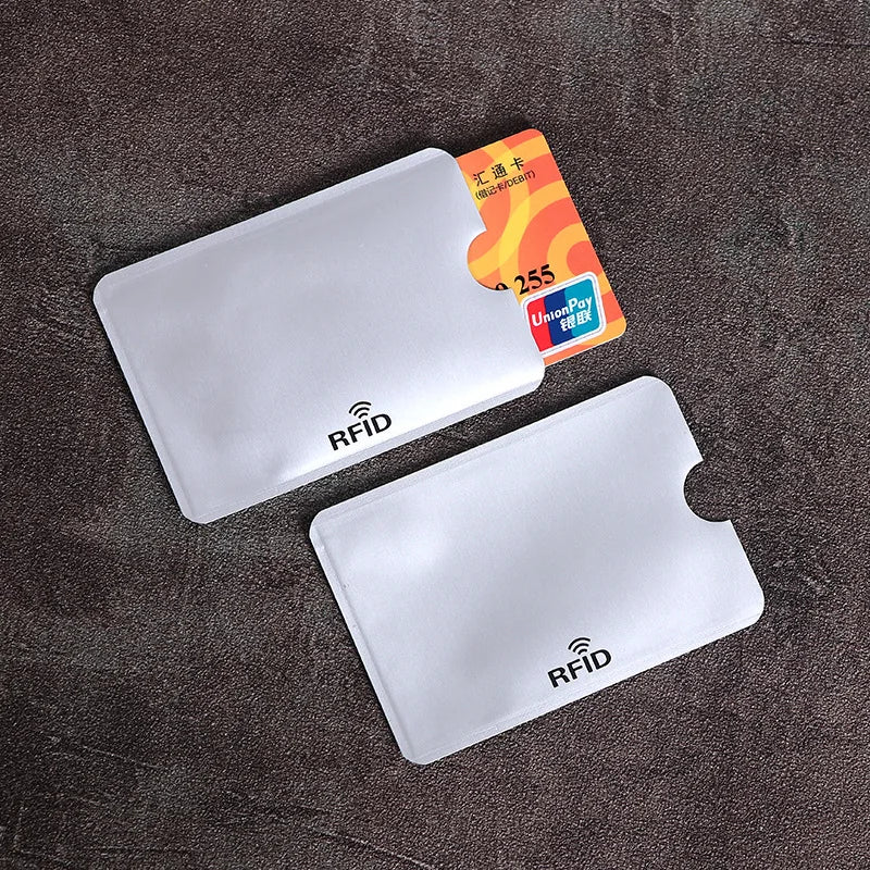 Two white, rectangular, thin plastic RFID-blocking sleeves for credit cards, with a thumb cutout.