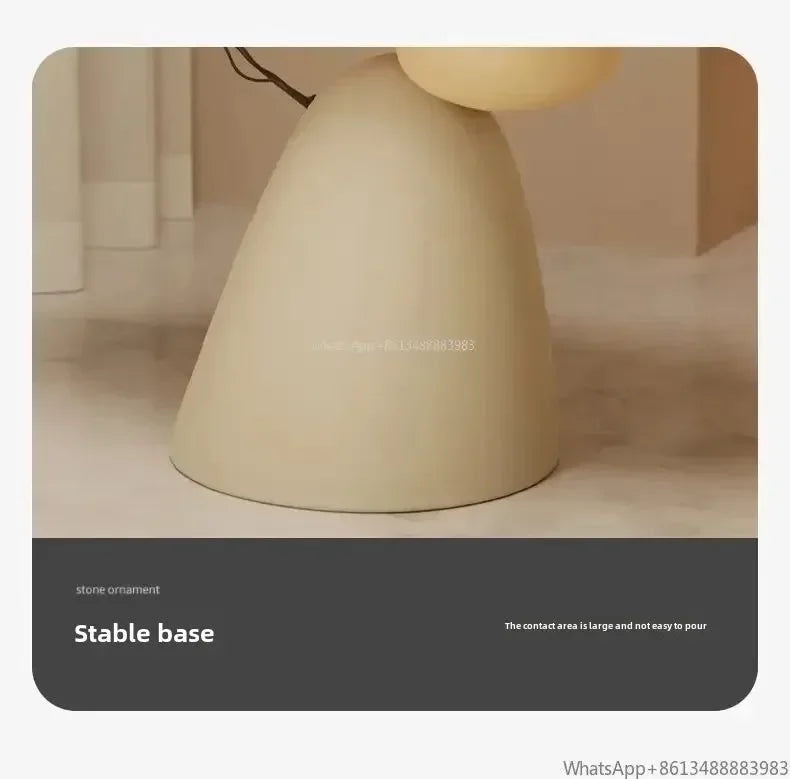 Minimalist cream-coloured side table with a wide, stable, bell-shaped stone base.