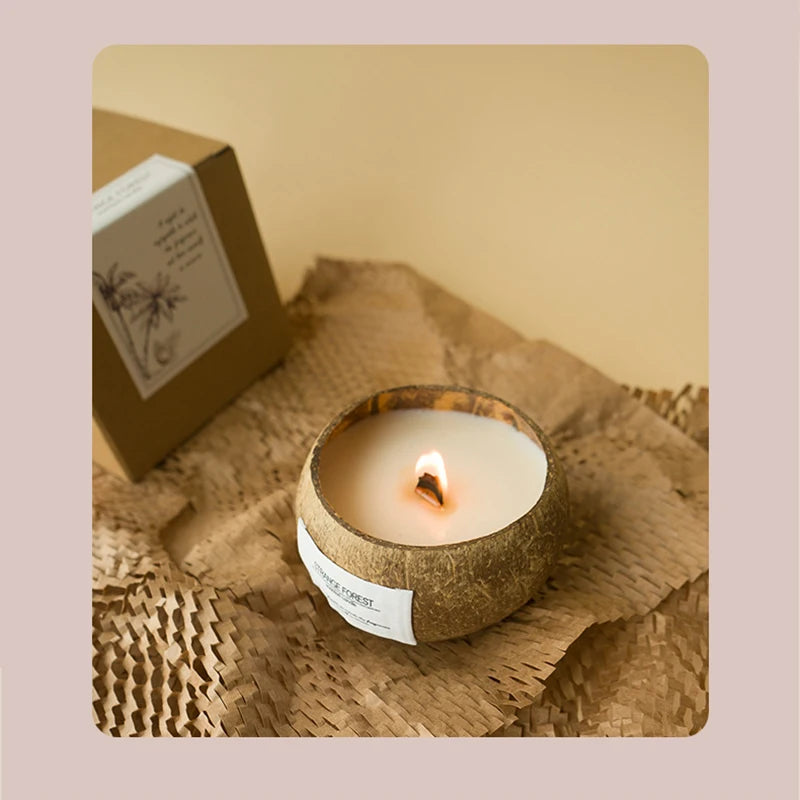 Burning white wax candle in a natural textured coconut shell container, presented on brown paper with a gift box.