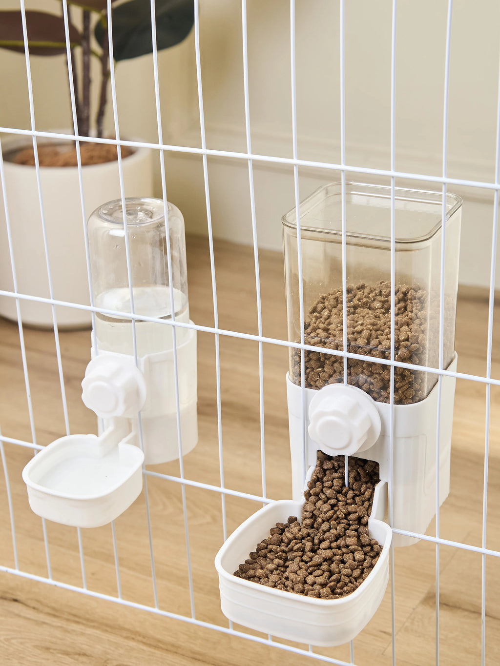 White cage-mounted pet food and water dispensers with clear containers and spill-proof bowls.