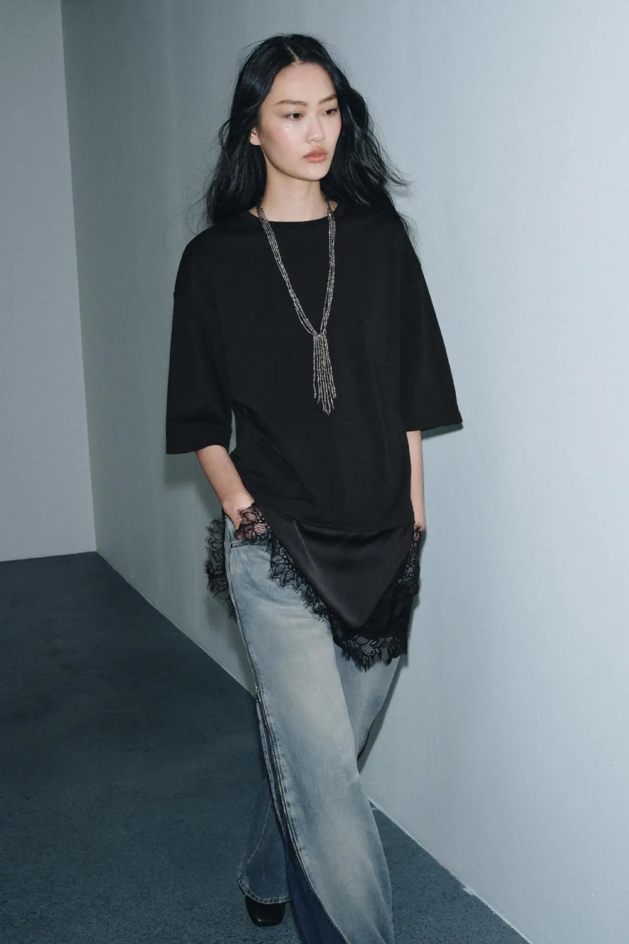 Black short-sleeved t-shirt with a satin hem and delicate lace trim, paired with light-wash blue jeans.