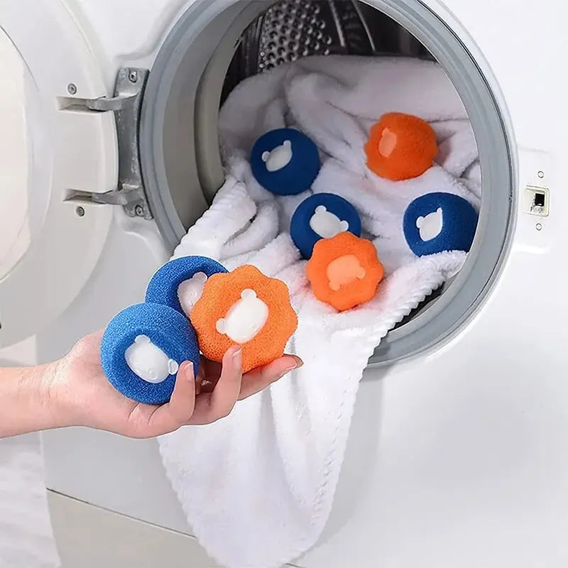 Hand holding orange and blue textured laundry lint remover balls with cute bear details in a washing machine.