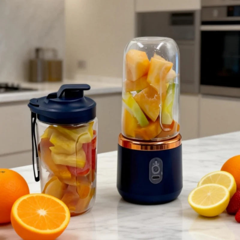 Portable personal blender with a navy base, copper trim, and clear blending jar filled with fruit, plus a spare cup.