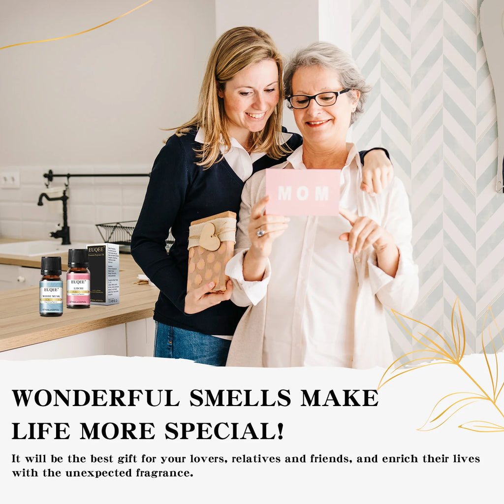 Two women smiling, holding a gift card and wrapped gift, with EUQEE 10ml fragrance oil bottles on the counter.
