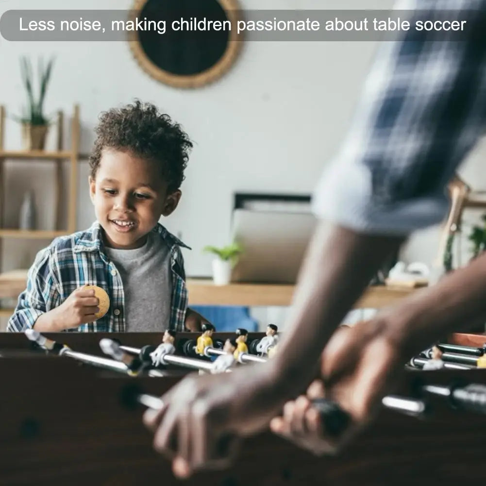 A young boy playing with a classic wooden foosball table, featuring metal rods and miniature football players.