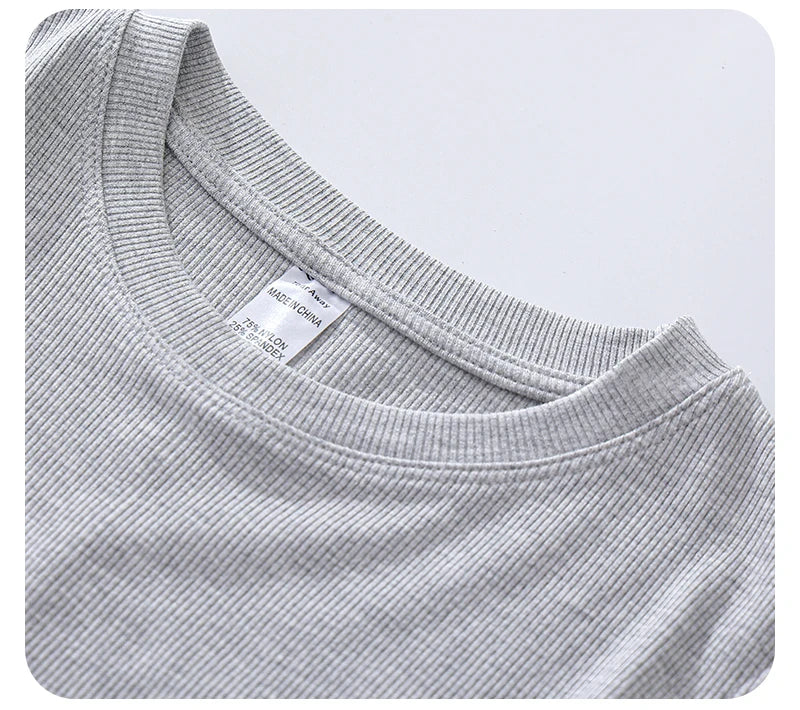 Close-up of a grey, ribbed crew-neck top showing the neckline texture and interior care label.