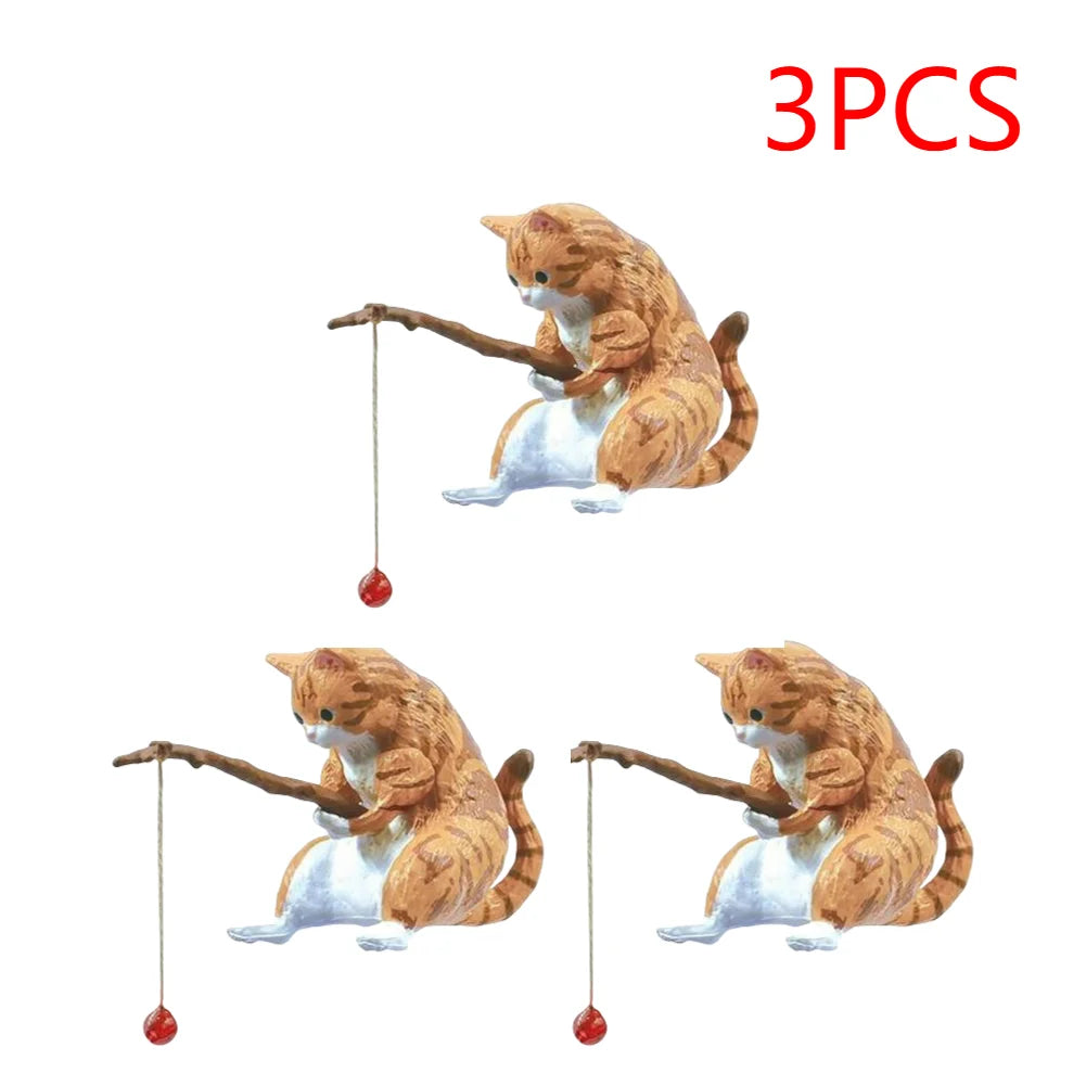 Three miniature ginger tabby cat ornaments, each holding a wooden fishing rod with a small red lure.