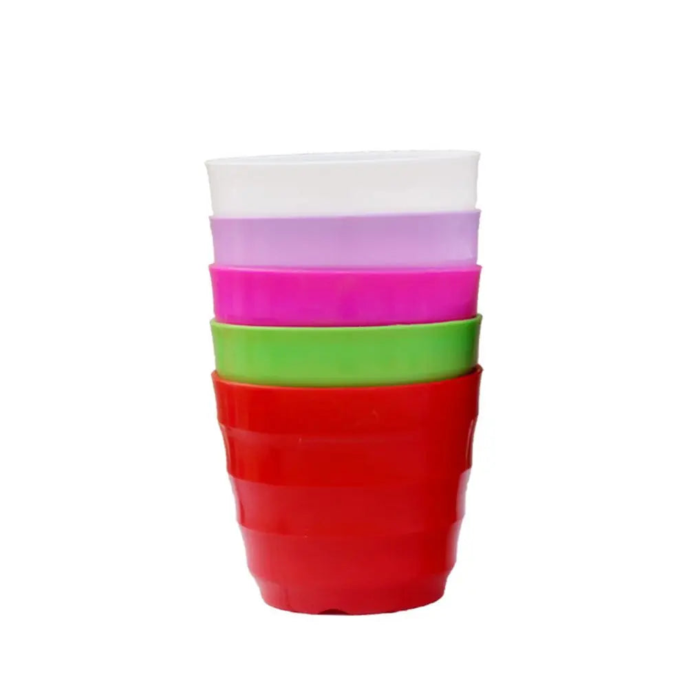 A stack of five colorful, ridged plastic flower pots in white, purple, pink, light green, and red against white.