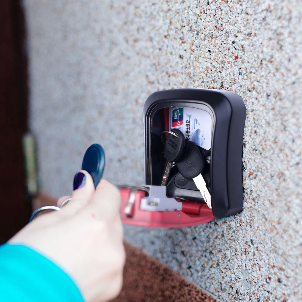 Wall-mounted black metal key lock box containing keys and a card, with a red door being opened by a key fob.