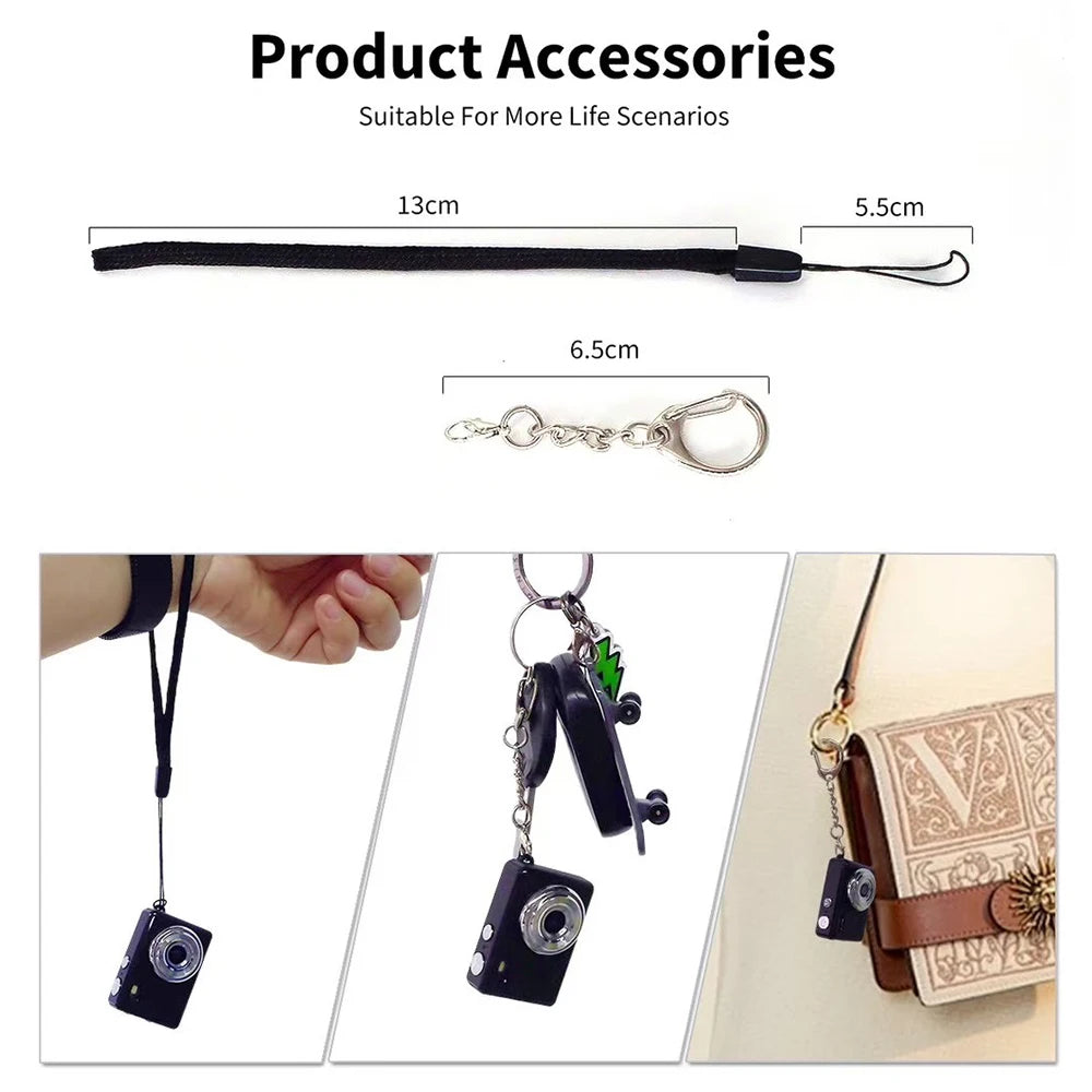 Black fabric wrist strap and metal keychain attachment for a small camera charm or key accessory.
