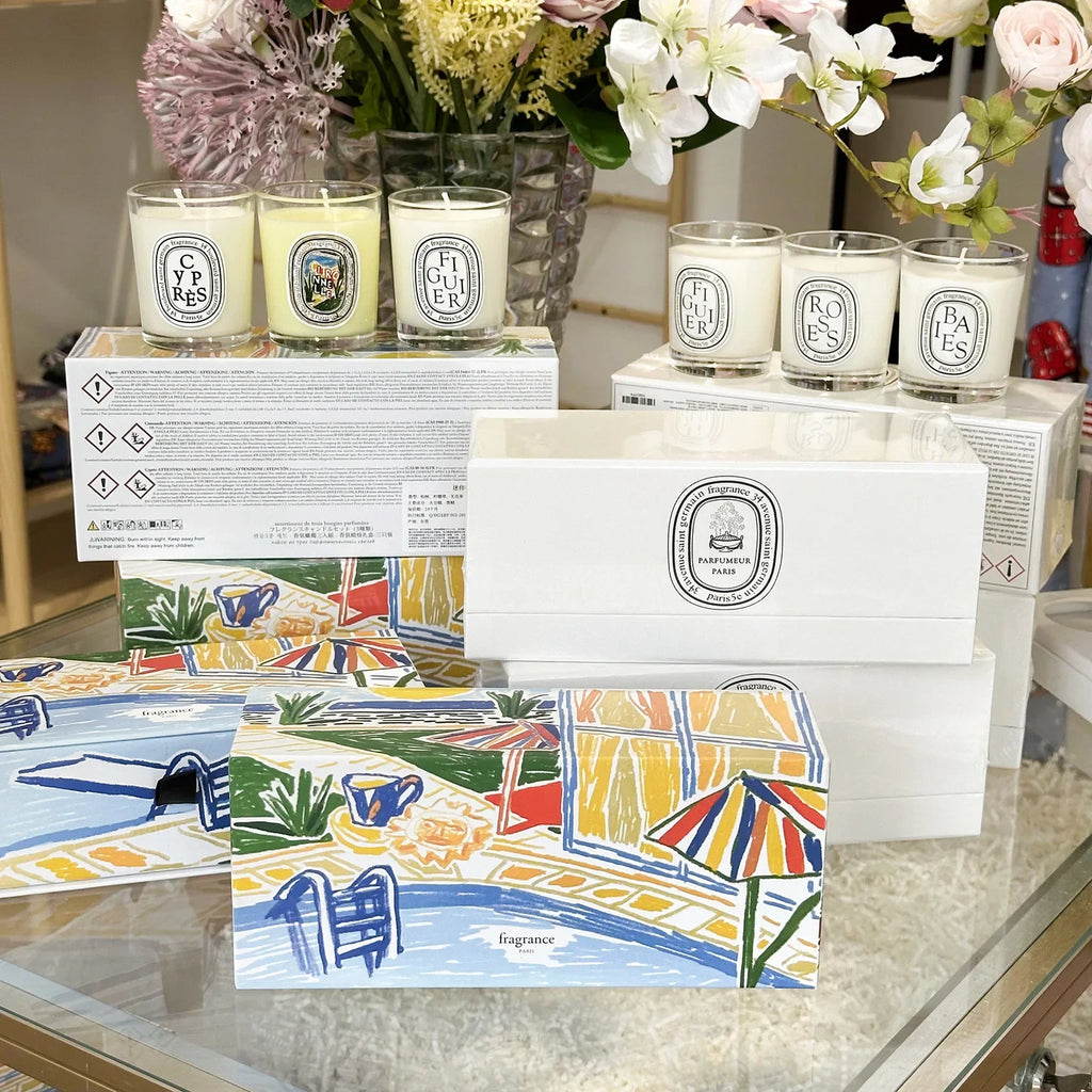 Set of scented glass jar candles presented in gift boxes featuring a colourful, illustrated summer poolside scene.