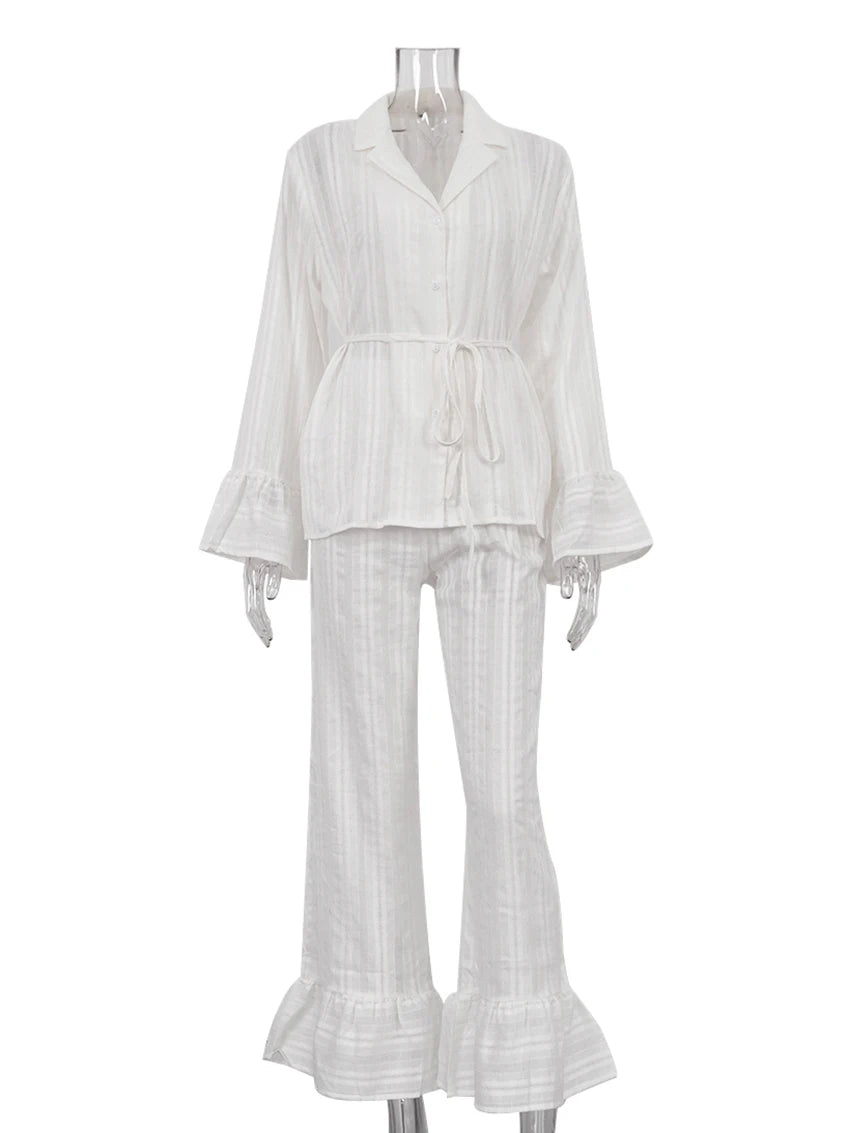 White striped lounge set with collared shirt, tie-waist, and flared, ruffle-hem sleeves and trousers.