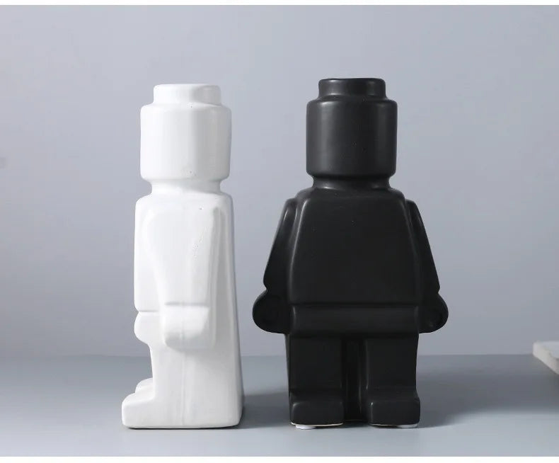 Two modern ceramic decorative figurines shaped like toy figures, one in matte white and one in matte black.