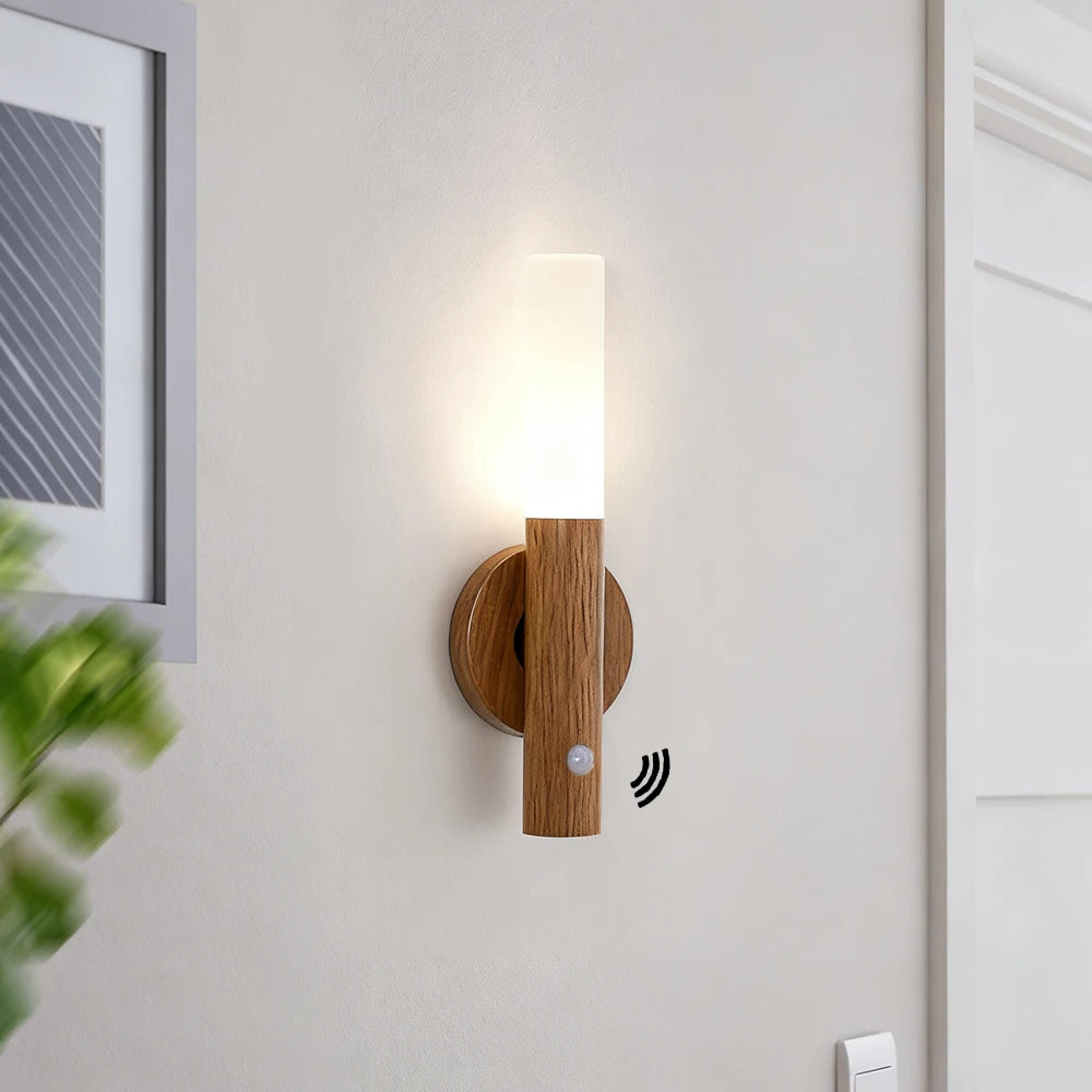 Minimalist wood-finish wall light with a frosted LED top, magnetic mount, and motion sensor, emitting a warm glow.