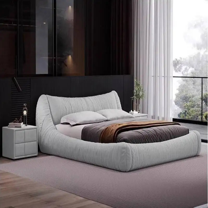 Contemporary pale grey upholstered bed frame with a curved, padded headboard and integrated storage base.