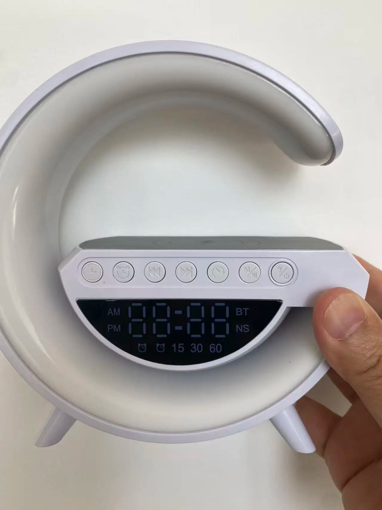 White circular LED alarm clock with digital display, wireless charging pad, Bluetooth controls, and built-in night light.