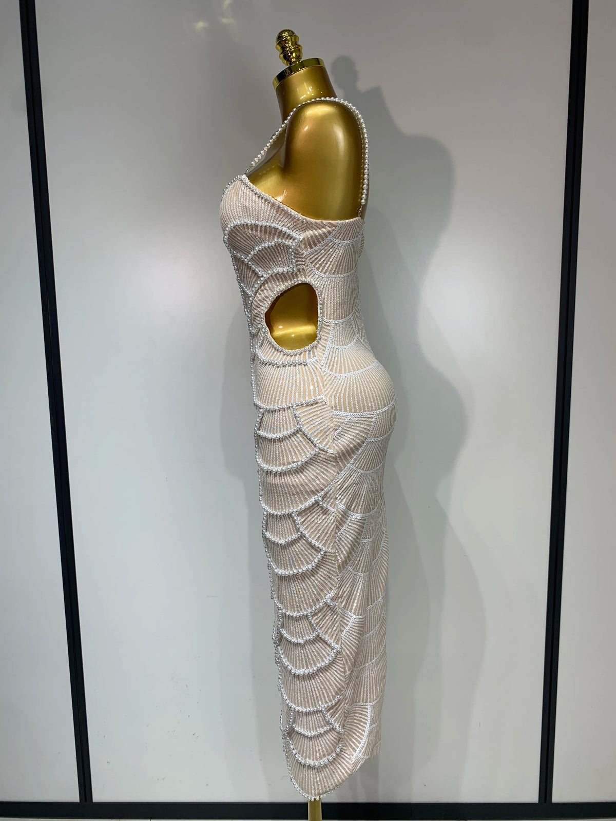 Beige bodycon maxi gown with pearl-beaded scalloped patterns and side cutout on a gold mannequin.