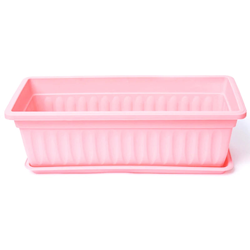 A rectangular, light pink plastic planter pot with vertical ridges and a matching removable drainage tray underneath.