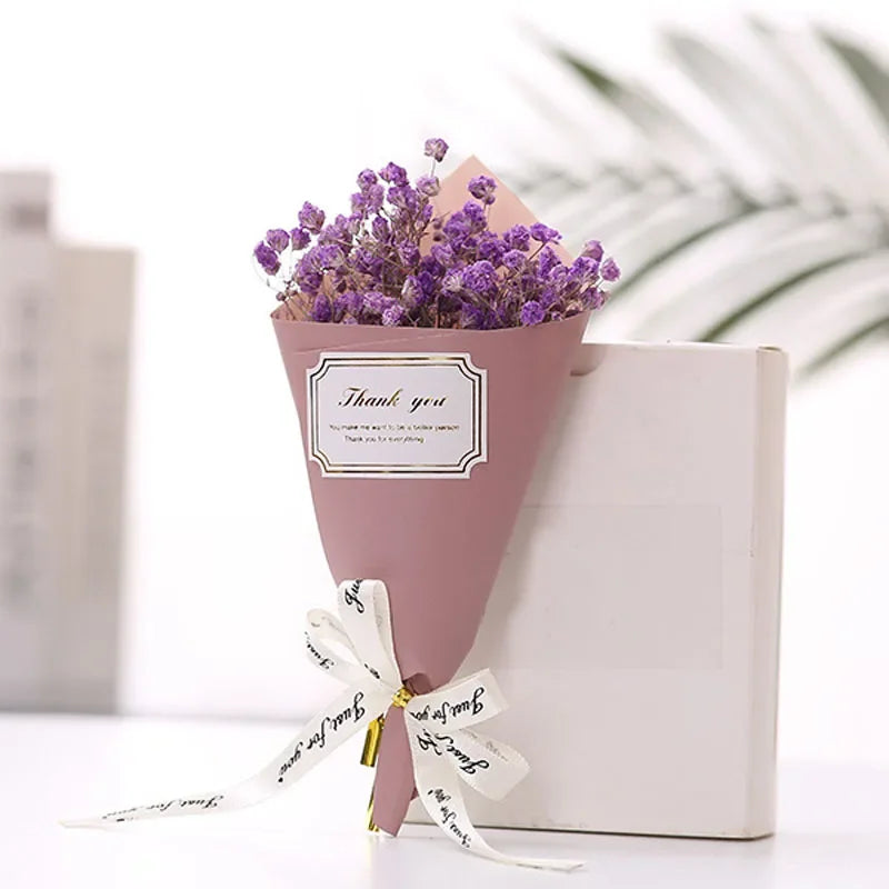 A small bouquet of purple gypsophila wrapped in dusty pink paper with a 'Thank you' label and decorative ribbon.