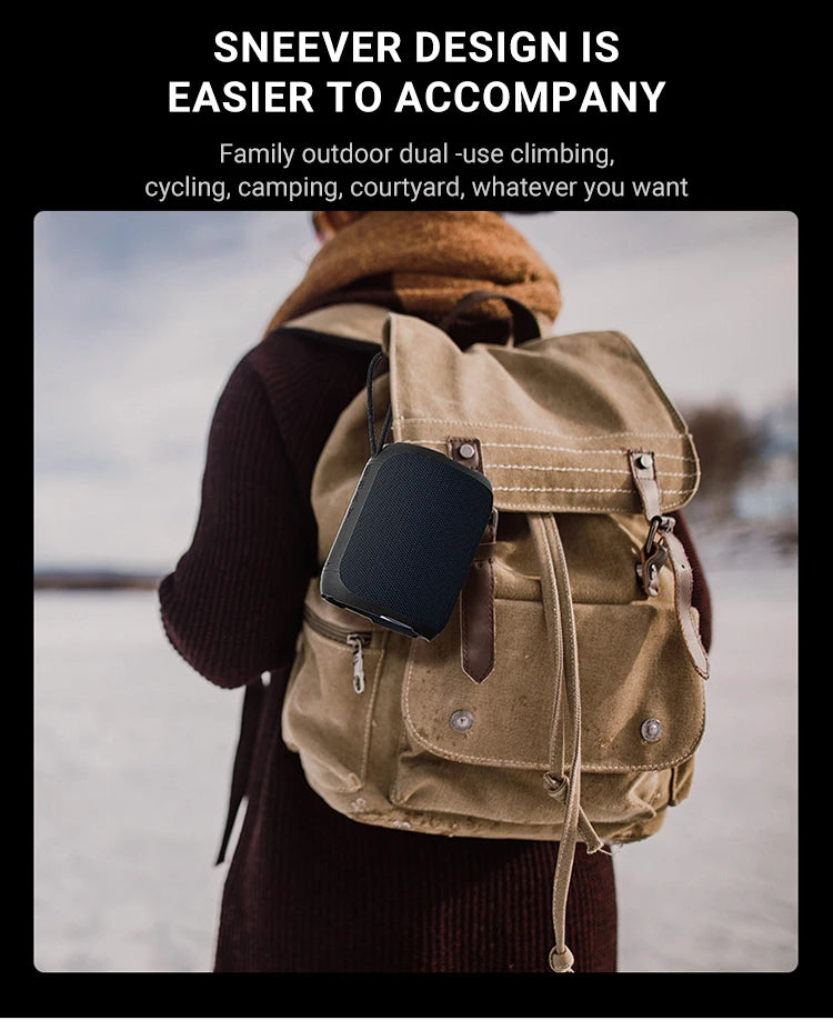 Black portable waterproof Bluetooth speaker hanging from a brown backpack outdoors.
