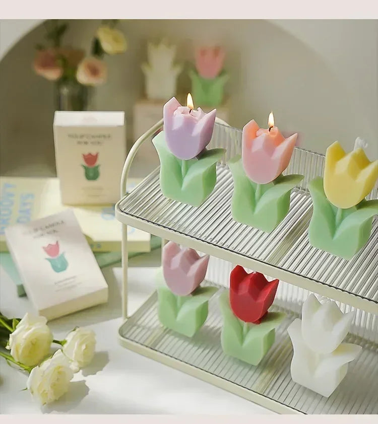 Set of six colourful, tulip-shaped wax candles with green bases, arranged on a two-tier tiered display tray.