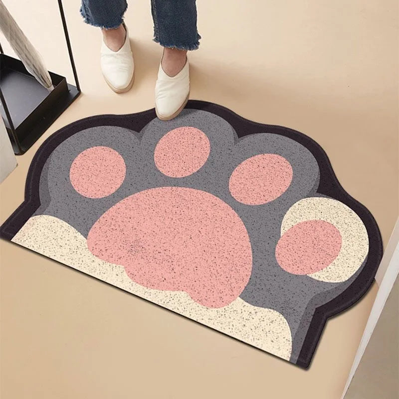 Grey and pink paw-shaped anti-slip cat litter mat with a textured surface on a plain floor.