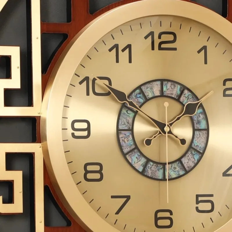 Modern gold-toned metal wall clock featuring black numerals and an iridescent mother-of-pearl centre detail.