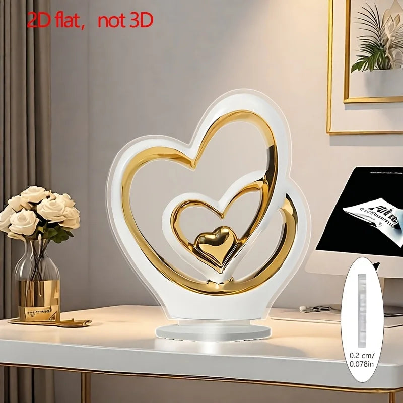 A modern, flat 2D white and gold heart-shaped ornament on a circular base, standing on a desk.