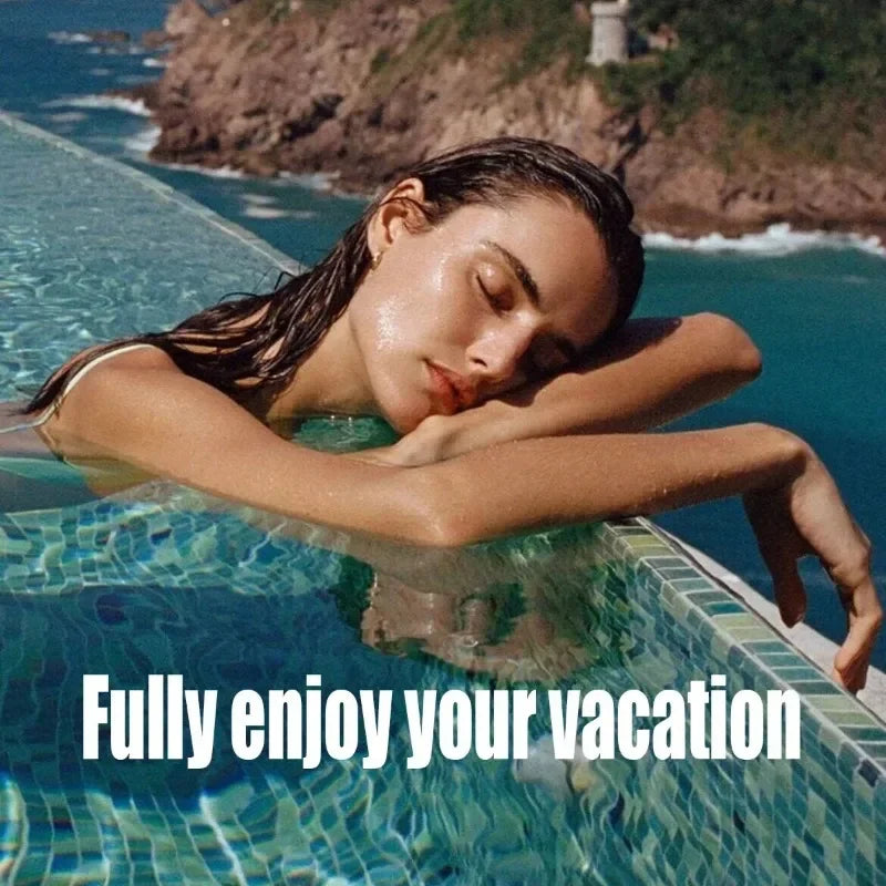 A woman with wet hair resting on the edge of a turquoise mosaic infinity pool overlooking the sea.
