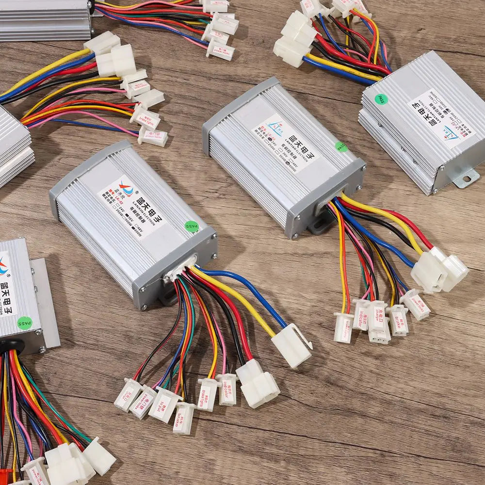 Silver rectangular e-bike brushed controllers with labeled multi-colored wires and white connectors on a wood surface.