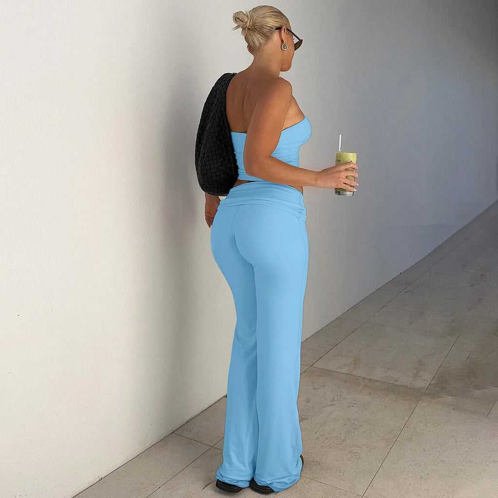 A woman wears a light blue two-piece set featuring a strapless crop top and matching high-waisted flared trousers.