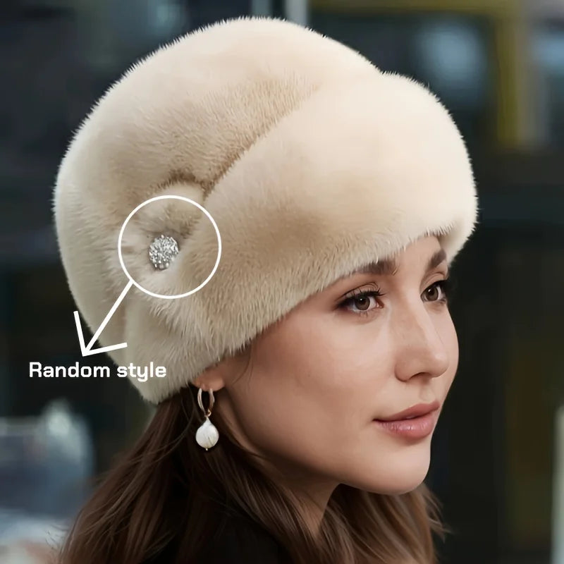 Elegant cream-coloured faux fur winter hat, featuring a soft, rounded silhouette and a decorative crystal embellishment.