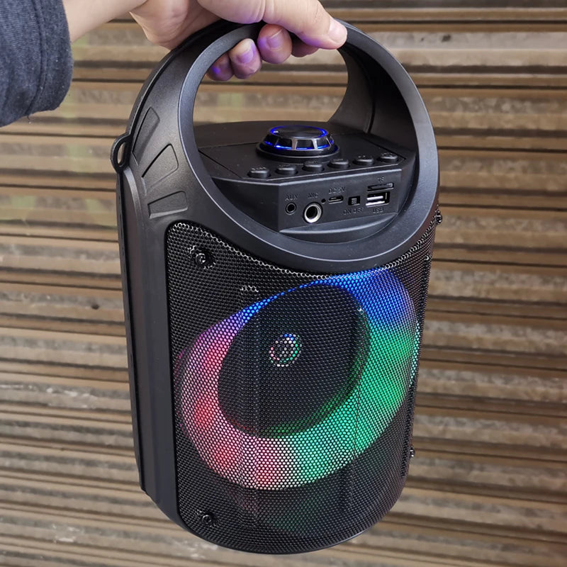 Portable black wireless speaker with a carry handle, mesh grille, and vibrant multicoloured LED light ring.