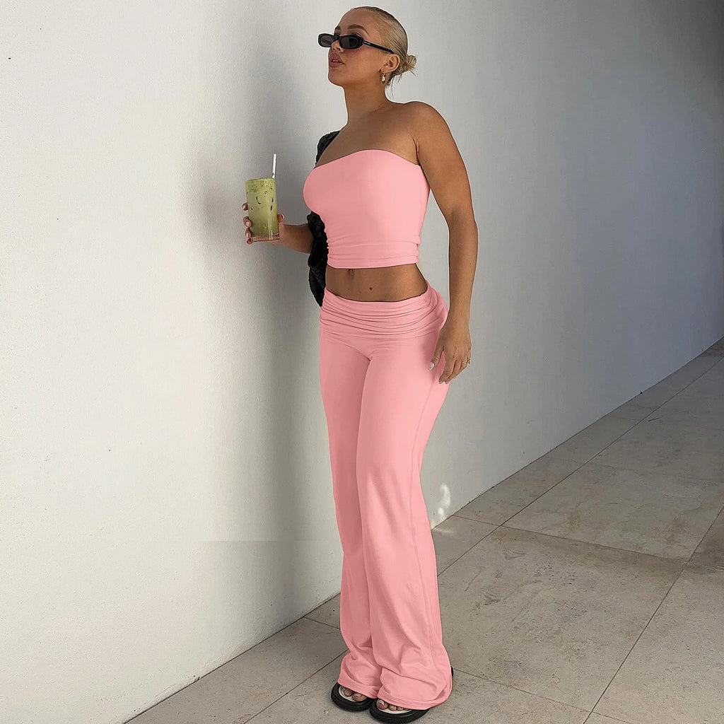 Woman wearing a pastel pink matching set with a cropped strapless tube top and high-waisted flared trousers.