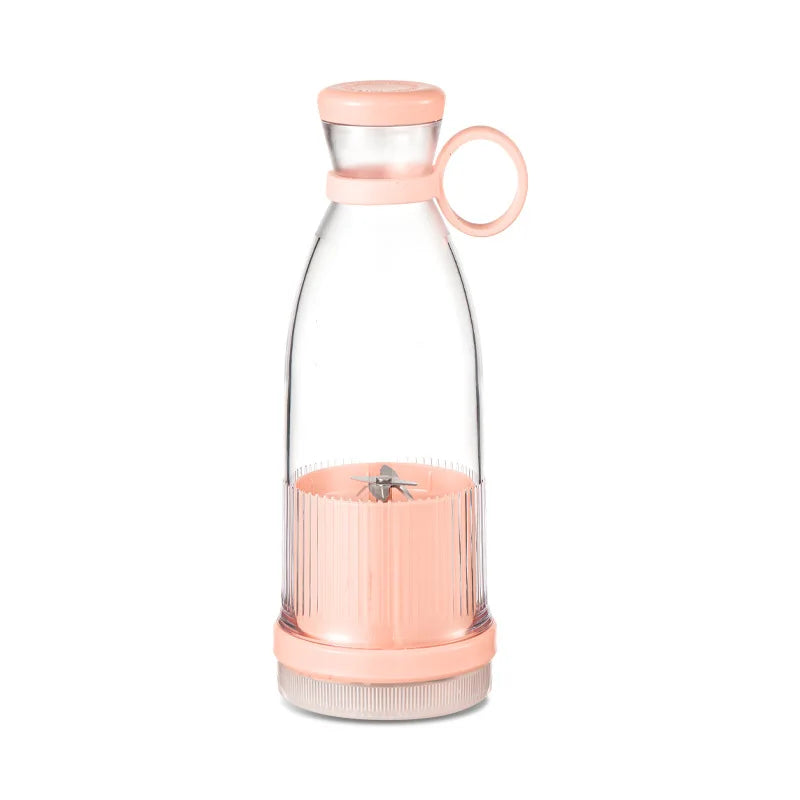 Portable personal blender in soft pink with a clear bottle, matching carry ring, and stainless steel blending blades.
