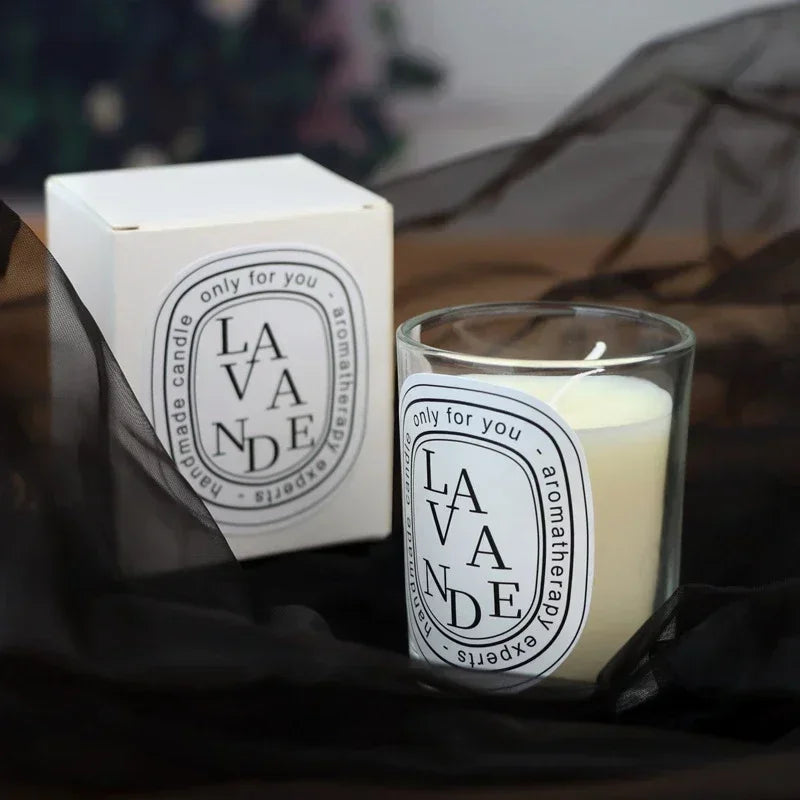 A white scented candle in a glass jar with a matching white box, featuring "Lavande" typography on black-rimmed labels.