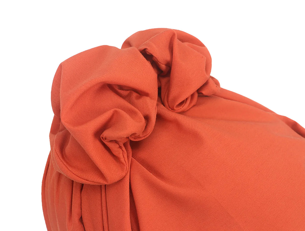 Close-up of a rust-orange French vintage-style turban hat featuring an elegant knotted detail.