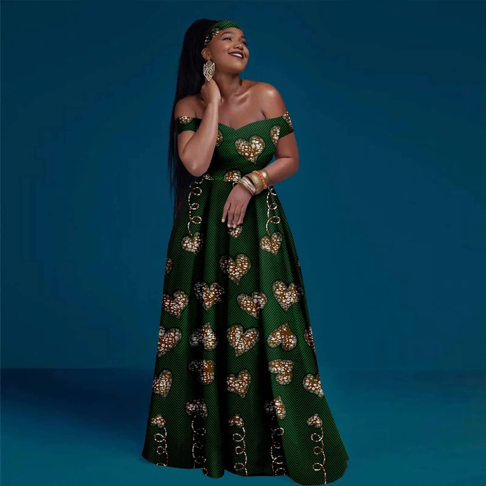 Green off-shoulder maxi dress with a V-neckline and repeating patterned heart print, styled with a matching headband.